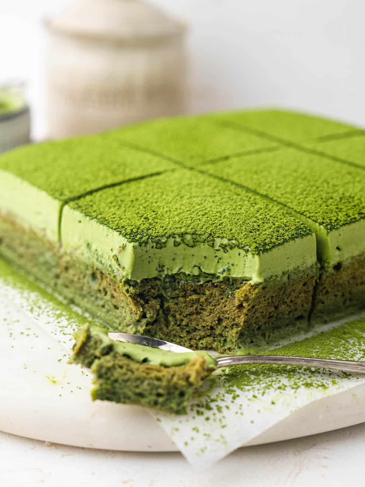 matcha tres leches cake topped with whipped cream and green tea powder