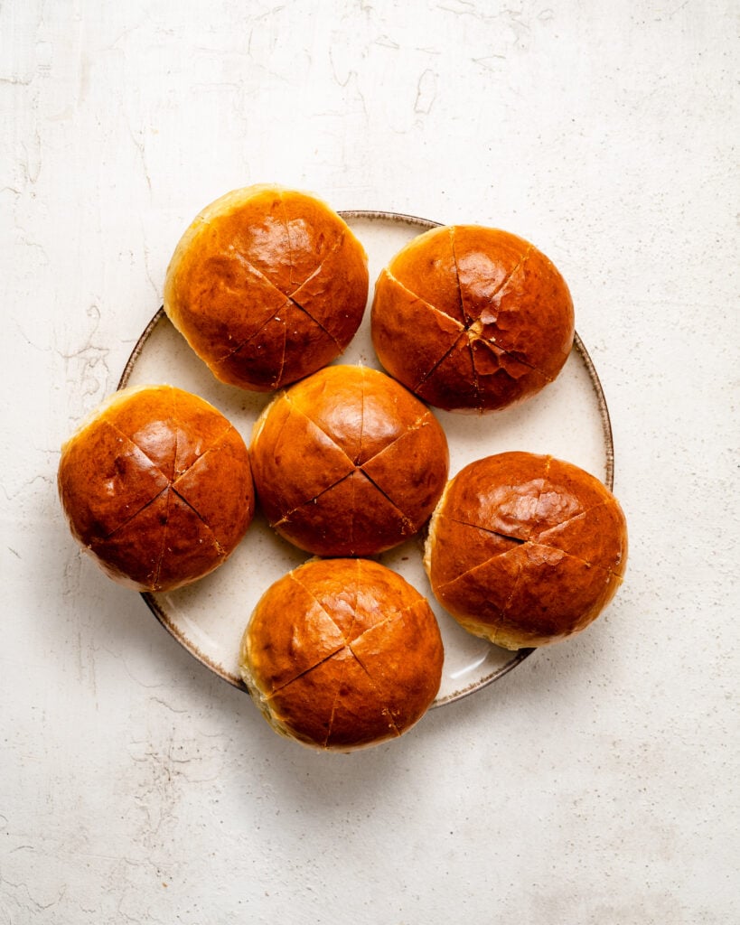 Glossy brown buns with cross cut lines prepared for Korean cream cheese garlic bread - Catherine Zhang Glossy brown buns with cross cut lines prepared for Korean cream cheese garlic bread