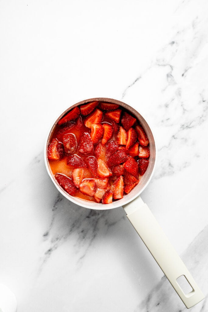 Korean Strawberry Milk sliced strawberries sitting in red-orange liquid in a saucepan - Catherine Zhang Korean Strawberry Milk sliced strawberries sitting in red-orange liquid in a saucepan