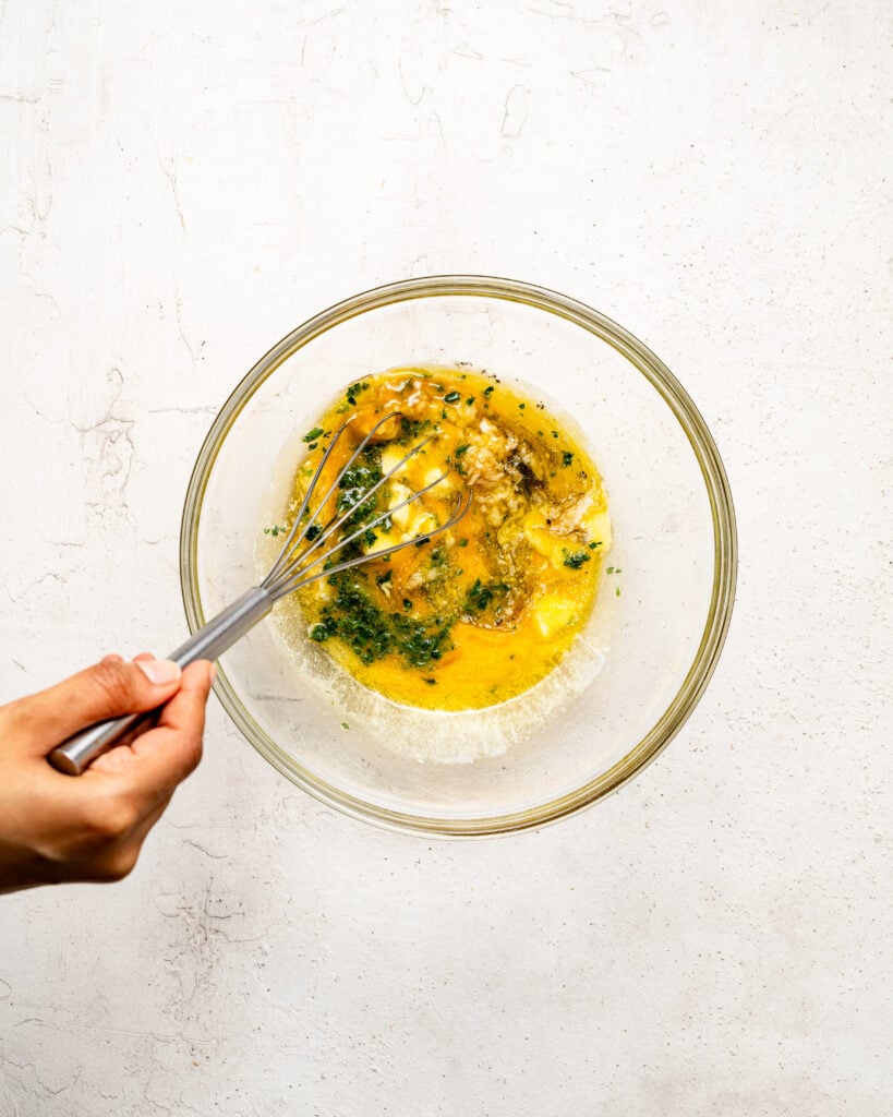 Whisking yellow butter mixture with herbs in a glass bowl - Catherine Zhang Whisking yellow butter mixture with herbs in a glass bowl