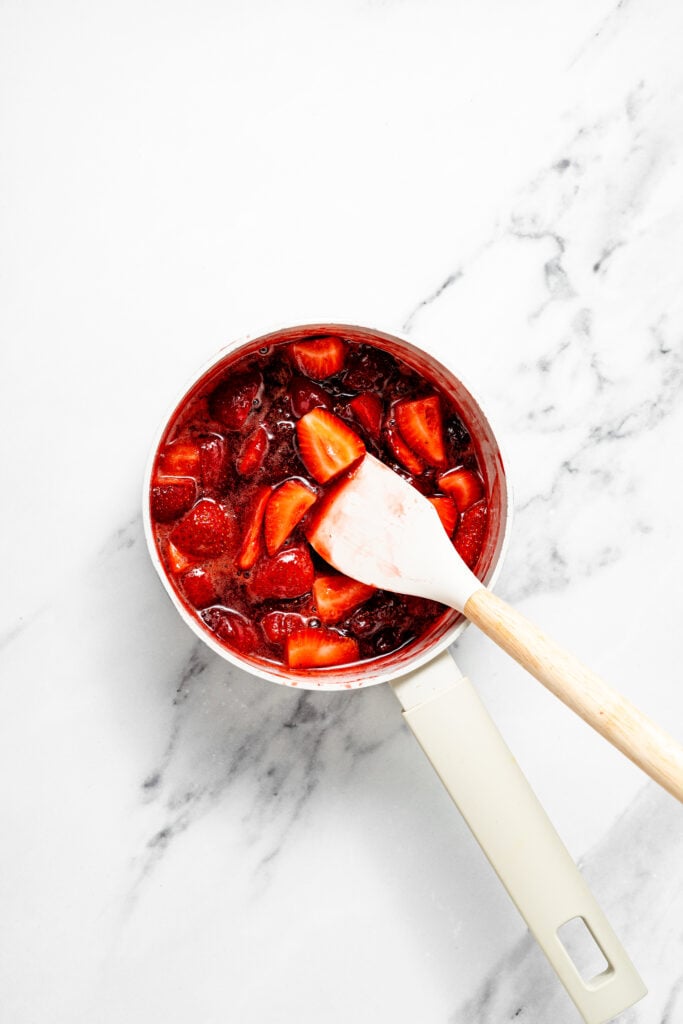 strawberry pieces in red liquid with a spatula in a saucepan - Catherine Zhang strawberry pieces in red liquid with a spatula in a saucepan