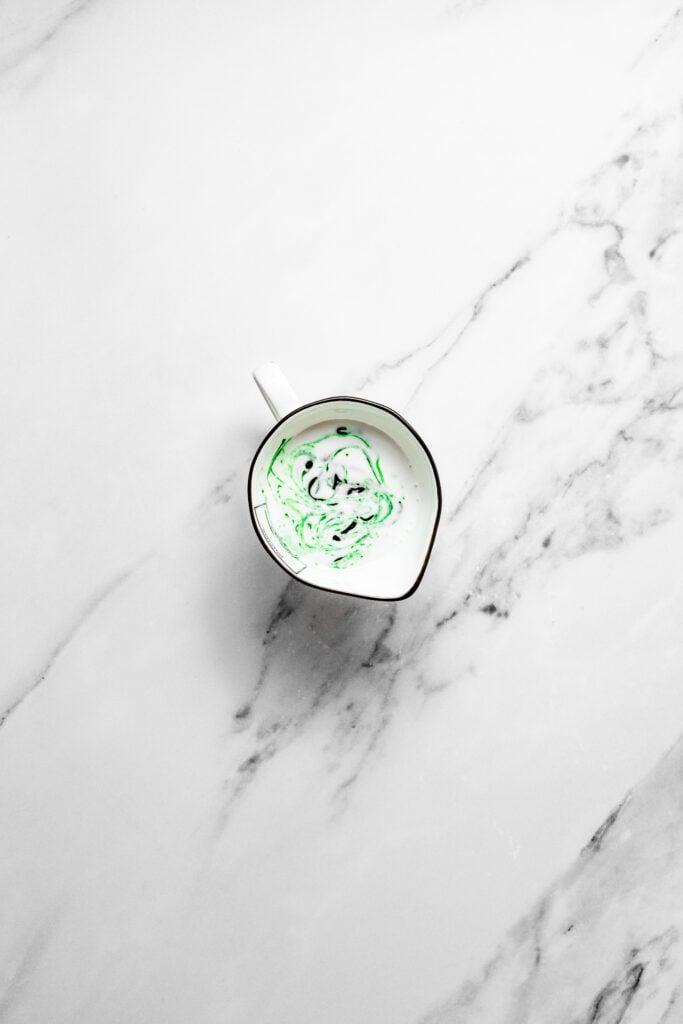 Coconut milk with green pandan mixture swirled in a small pouring cup for pandan chiffon cake - Catherine Zhang Coconut milk with green pandan mixture swirled in a small pouring cup for pandan chiffon cake