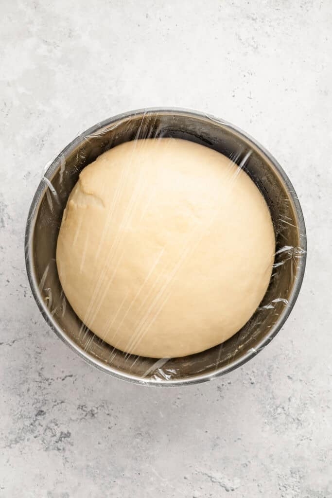 Covered Melon Pan dough ball resting in a metal bowl