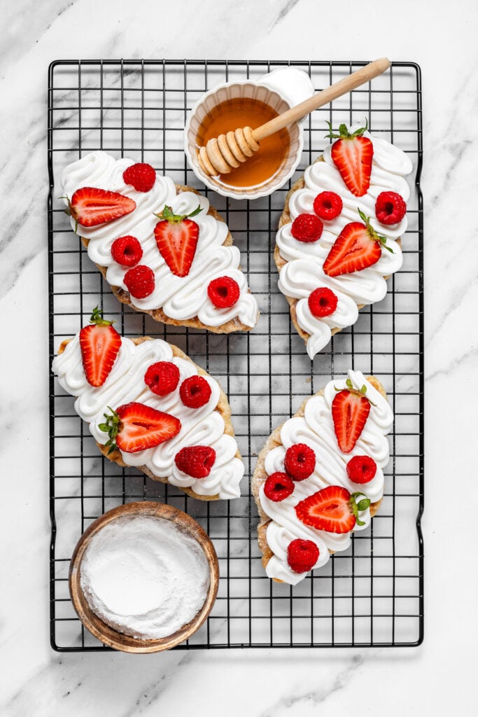 Croffles topped with whipped cream strawberries raspberries and honey on a wire rack - Catherine Zhang Croffles topped with whipped cream strawberries raspberries and honey on a wire rack
