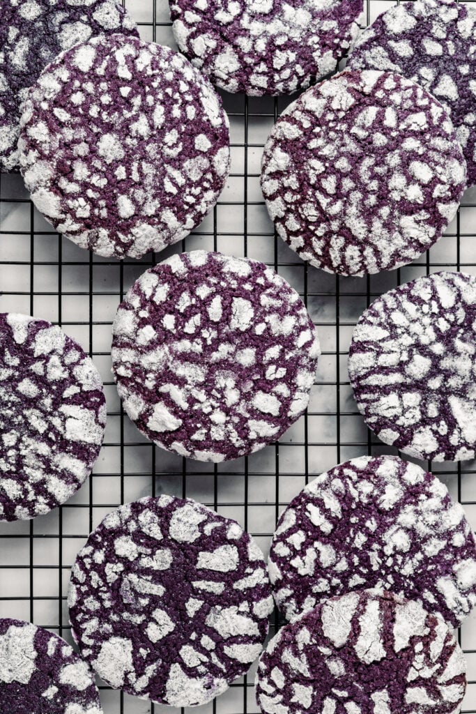 Finished Ube Crinkle Cookies cooling on a black wire rack - Catherine Zhang Finished Ube Crinkle Cookies cooling on a black wire rack