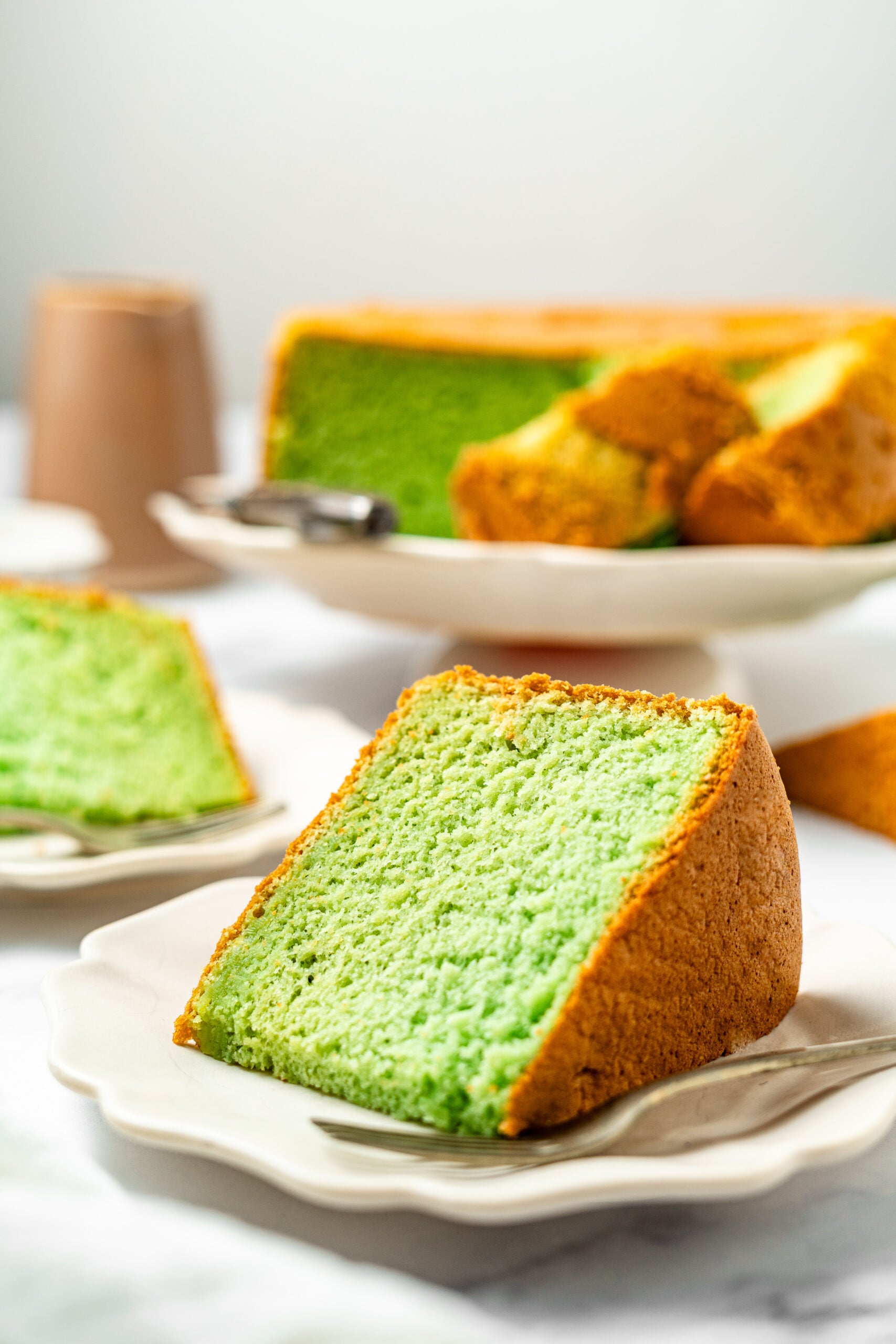 Pandan coconut cake - Catherine Zhang Slices of bright green matcha pound cake on white plates, with a loaf of green-crumb cake in the background