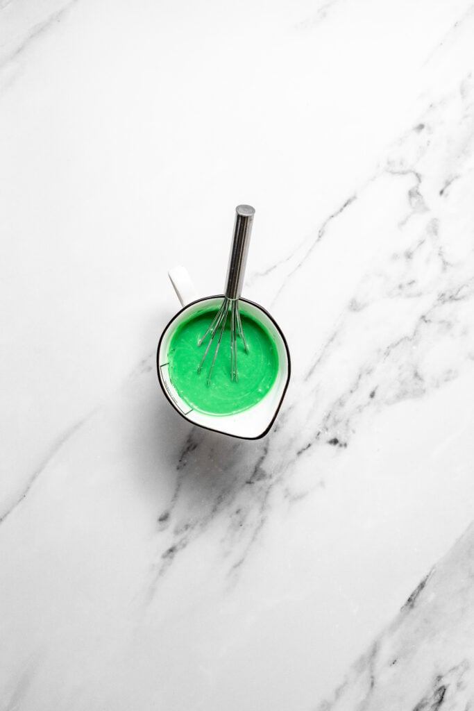Smooth green pandan milk mixture in a small pouring cup with a whisk - Catherine Zhang Smooth green pandan milk mixture in a small pouring cup with a whisk