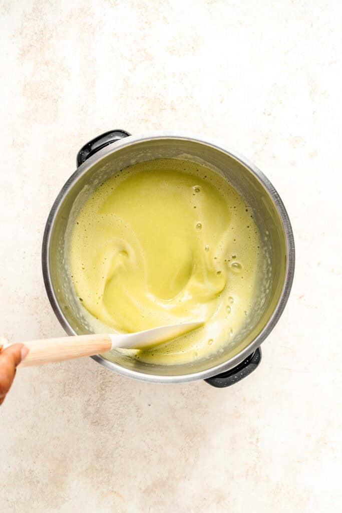 Stirring thickening pale green Pandan Kaya Jam with a silicone spatula - Catherine Zhang Stirring thickening pale green Pandan Kaya Jam with a silicone spatula