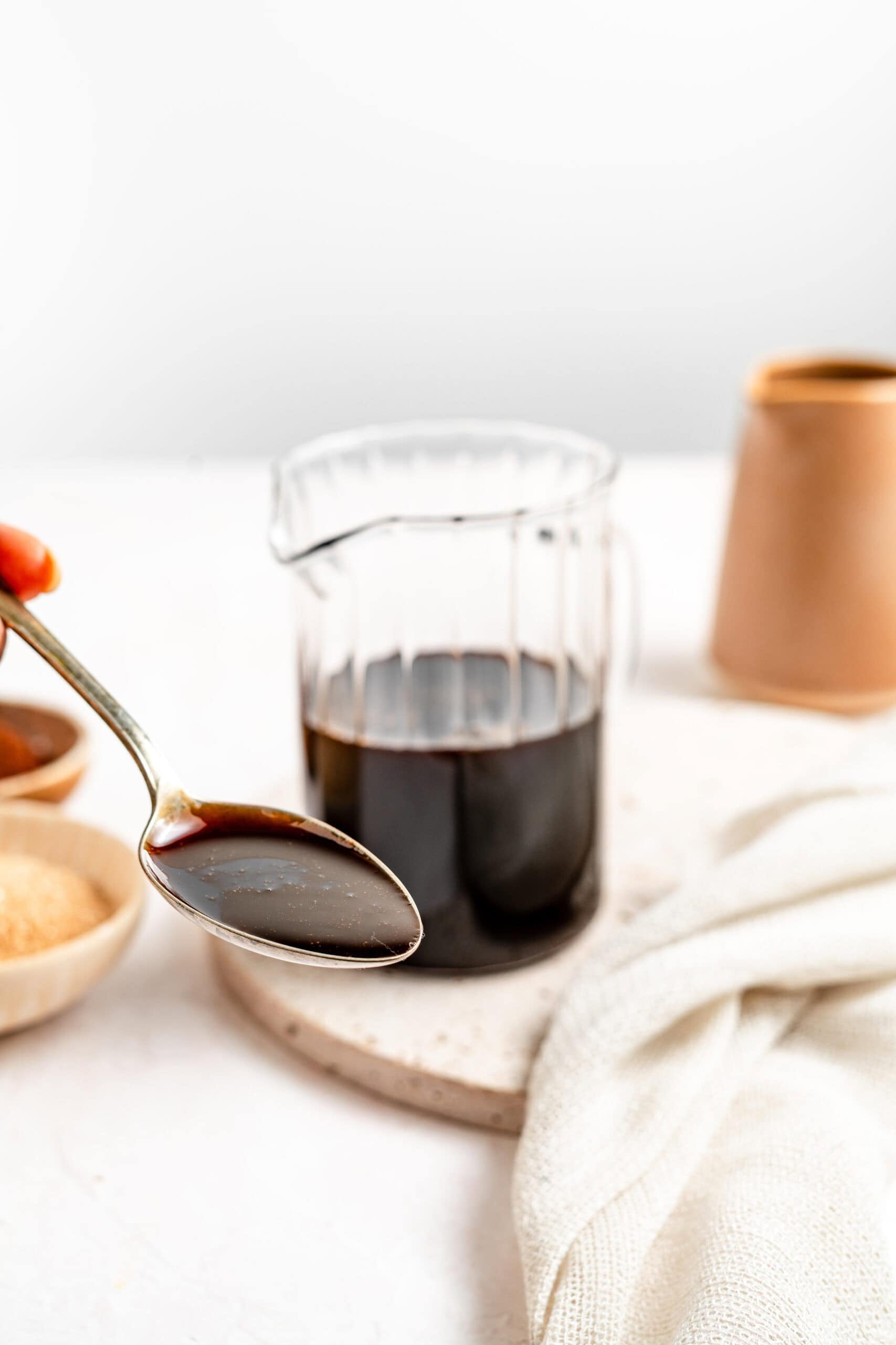 A glass of kuromitsu black sugar syrup styled with a spoon - Catherine Zhang A glass of kuromitsu black sugar syrup styled with a spoon