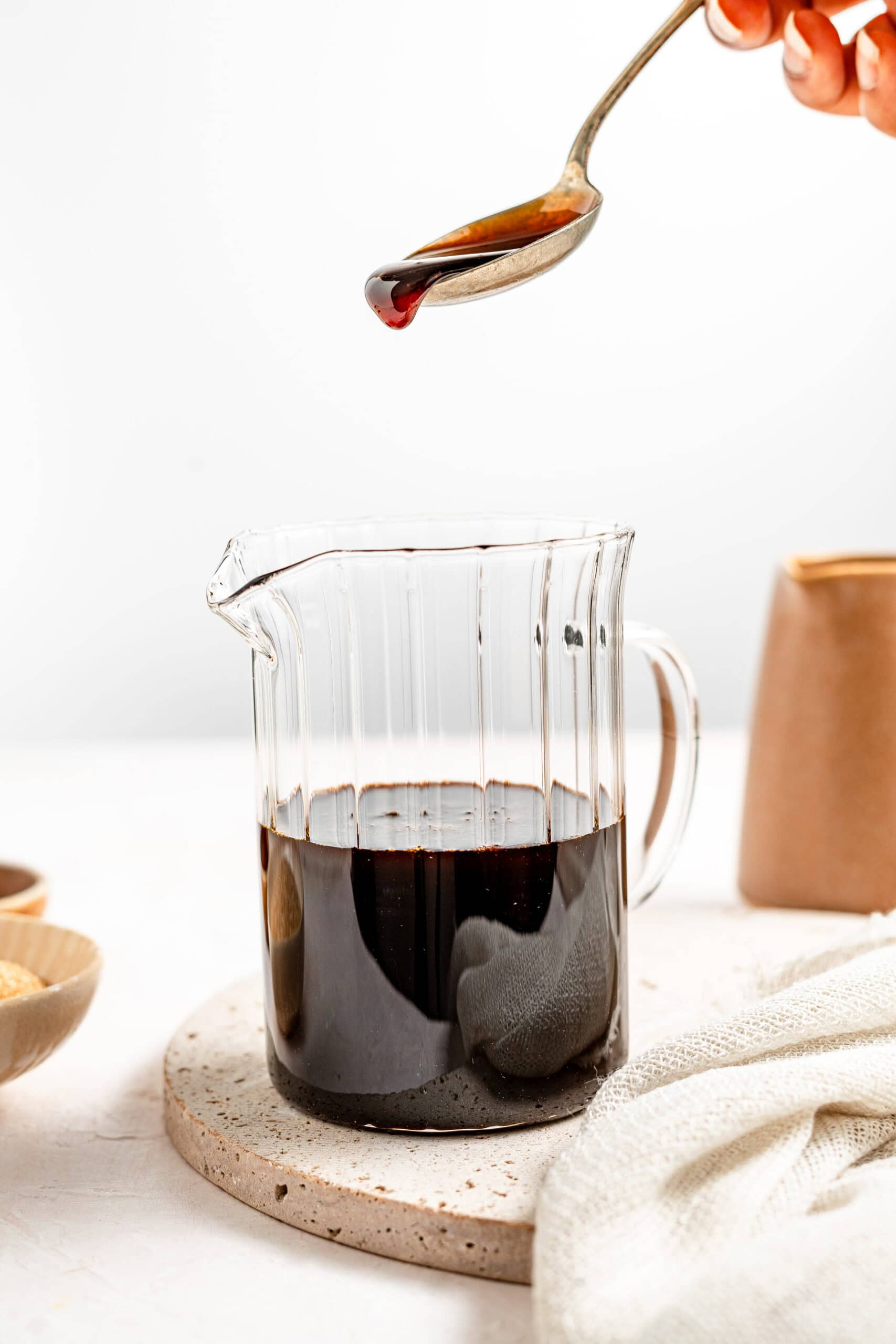 A spoon lifting glossy kuromitsu syrup to show its thickness - Catherine Zhang A spoon lifting glossy kuromitsu syrup to show its thickness