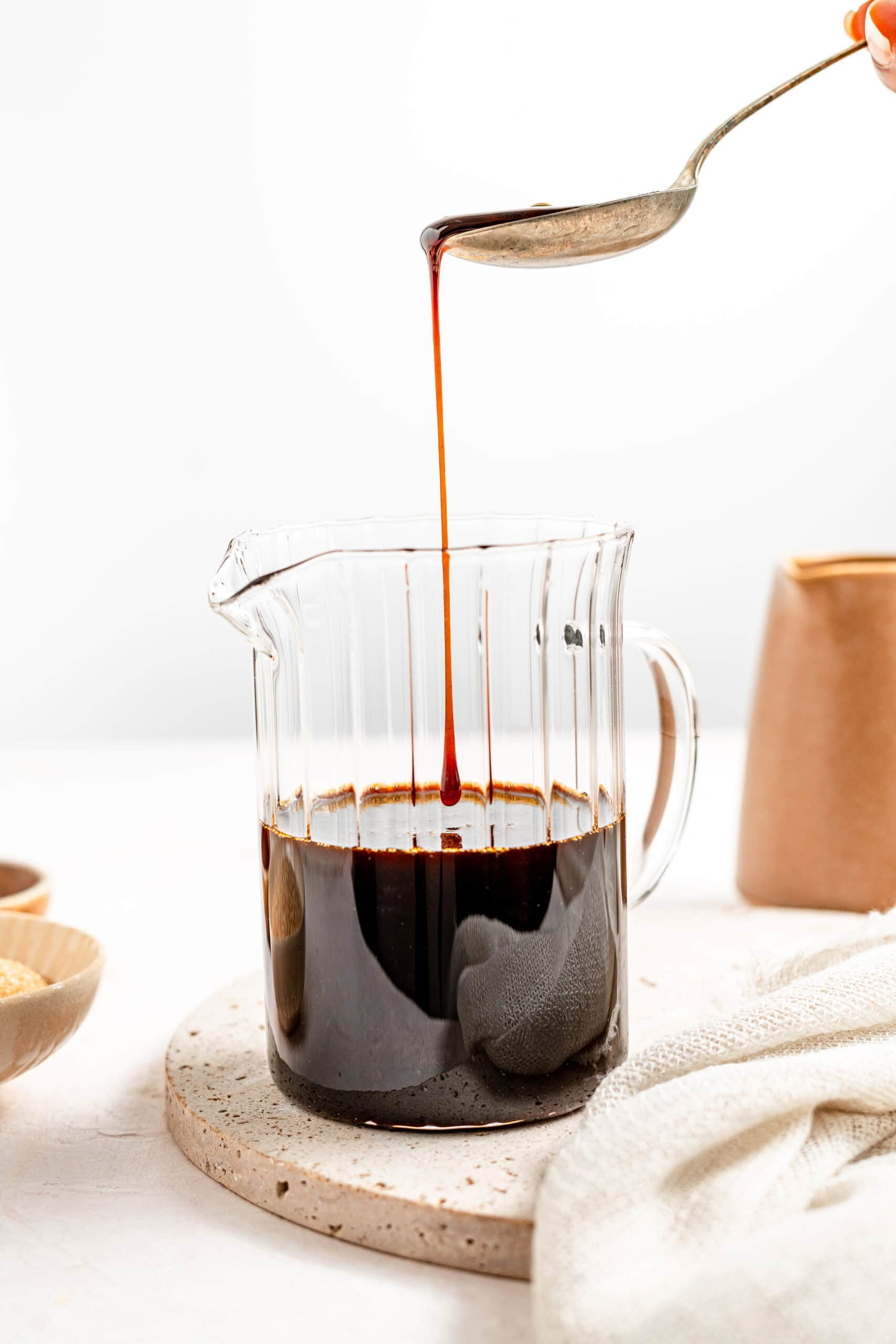 Kuromitsu syrup being drizzled from a spoon into a glass - Catherine Zhang Kuromitsu syrup being drizzled from a spoon into a glass