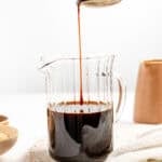 Kuromitsu Japanese black sugar syrup drizzling from a spoon into a glass beaker