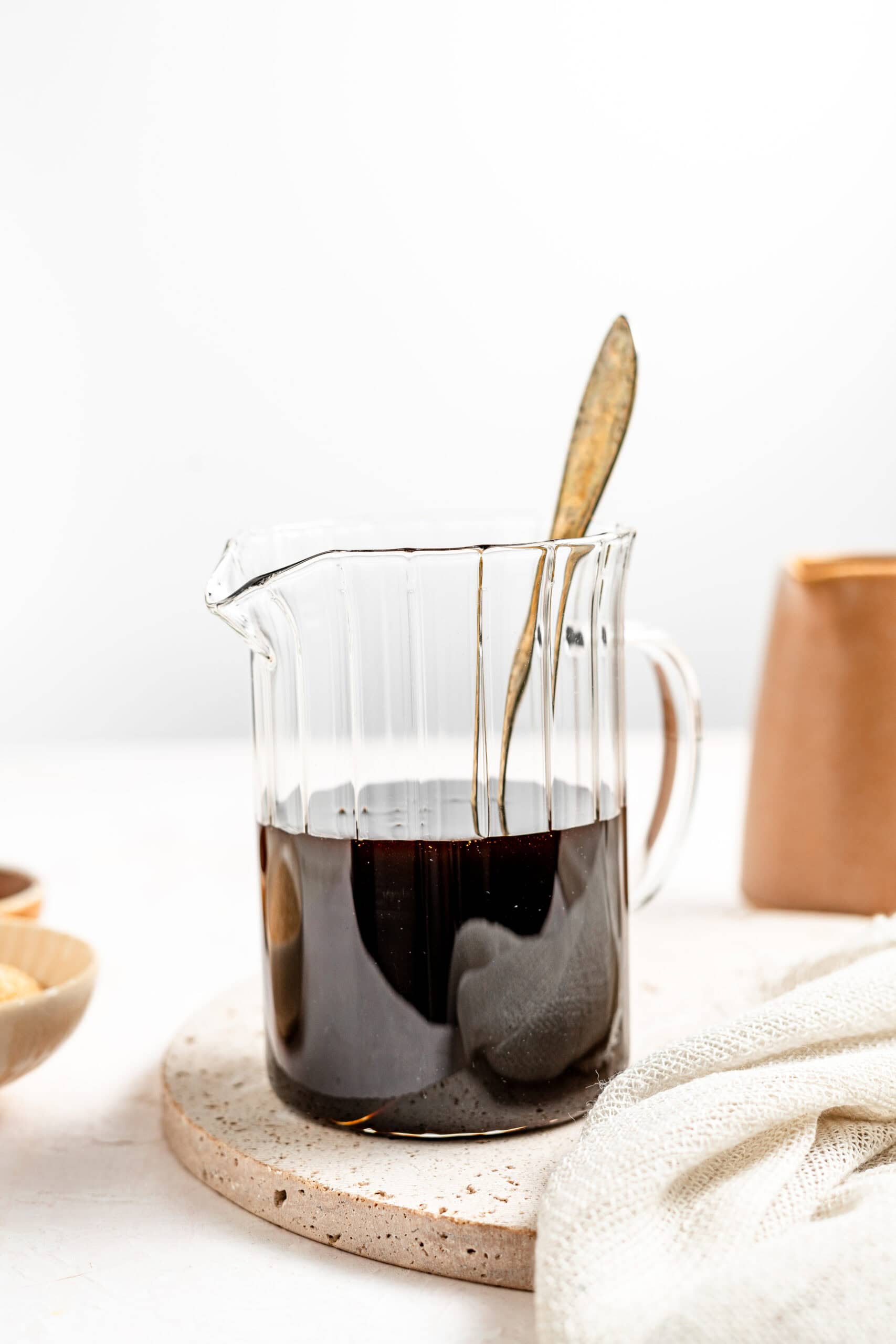 Glass beaker of homemade kuromitsu Japanese black sugar syrup with copper cups - Catherine Zhang Glass beaker of homemade kuromitsu Japanese black sugar syrup with copper cups