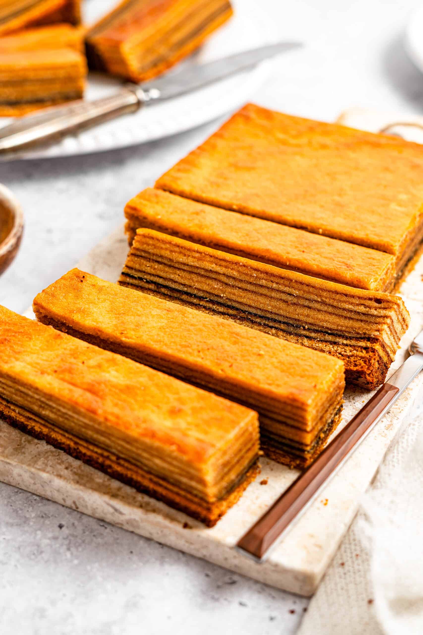 Lapis legit slices served on a cake stand - Catherine Zhang Rectangular slices of layered honey cake arranged on a cutting board on a light surface, close-up view.