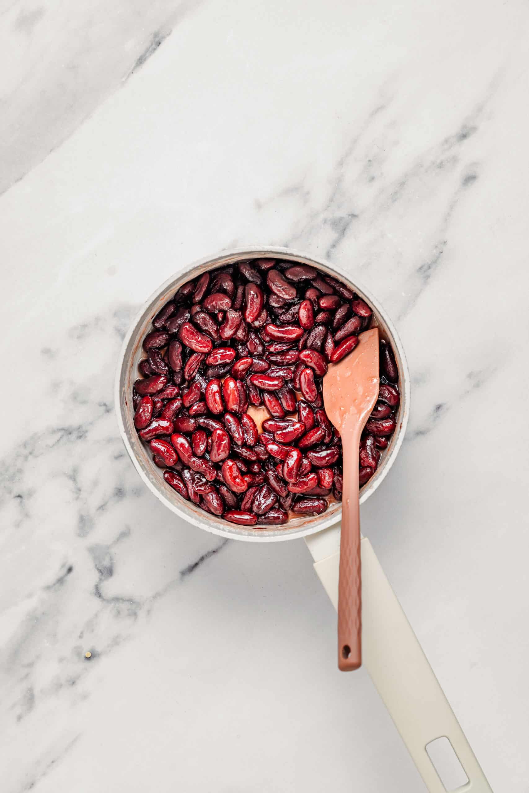 Glossy sweetened red beans stirred with a spatula for the che ba mau red bean layer - Catherine Zhang Glossy sweetened red beans stirred with a spatula until they coat the spoon