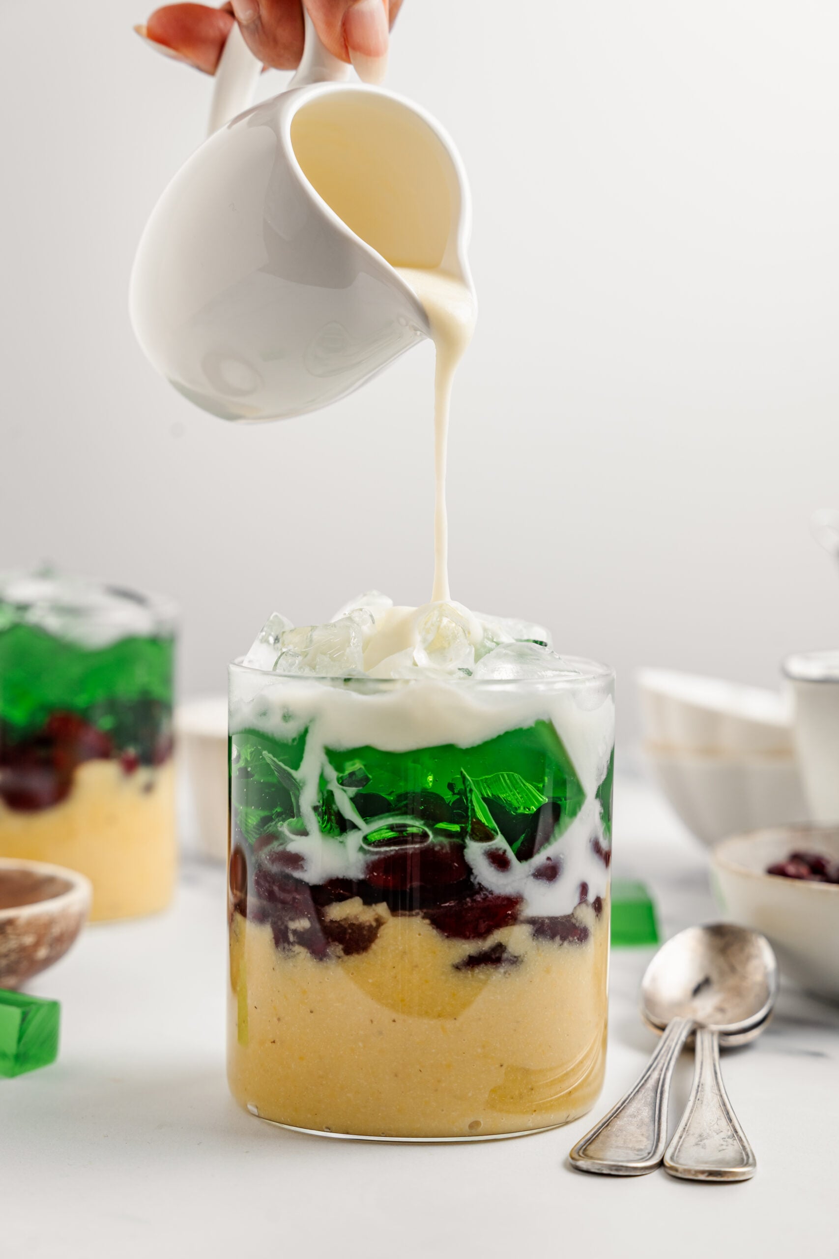 Pouring cold coconut sauce over crushed ice on a glass of che ba mau - Catherine Zhang Pouring cold coconut sauce over the crushed ice on a glass of che ba mau