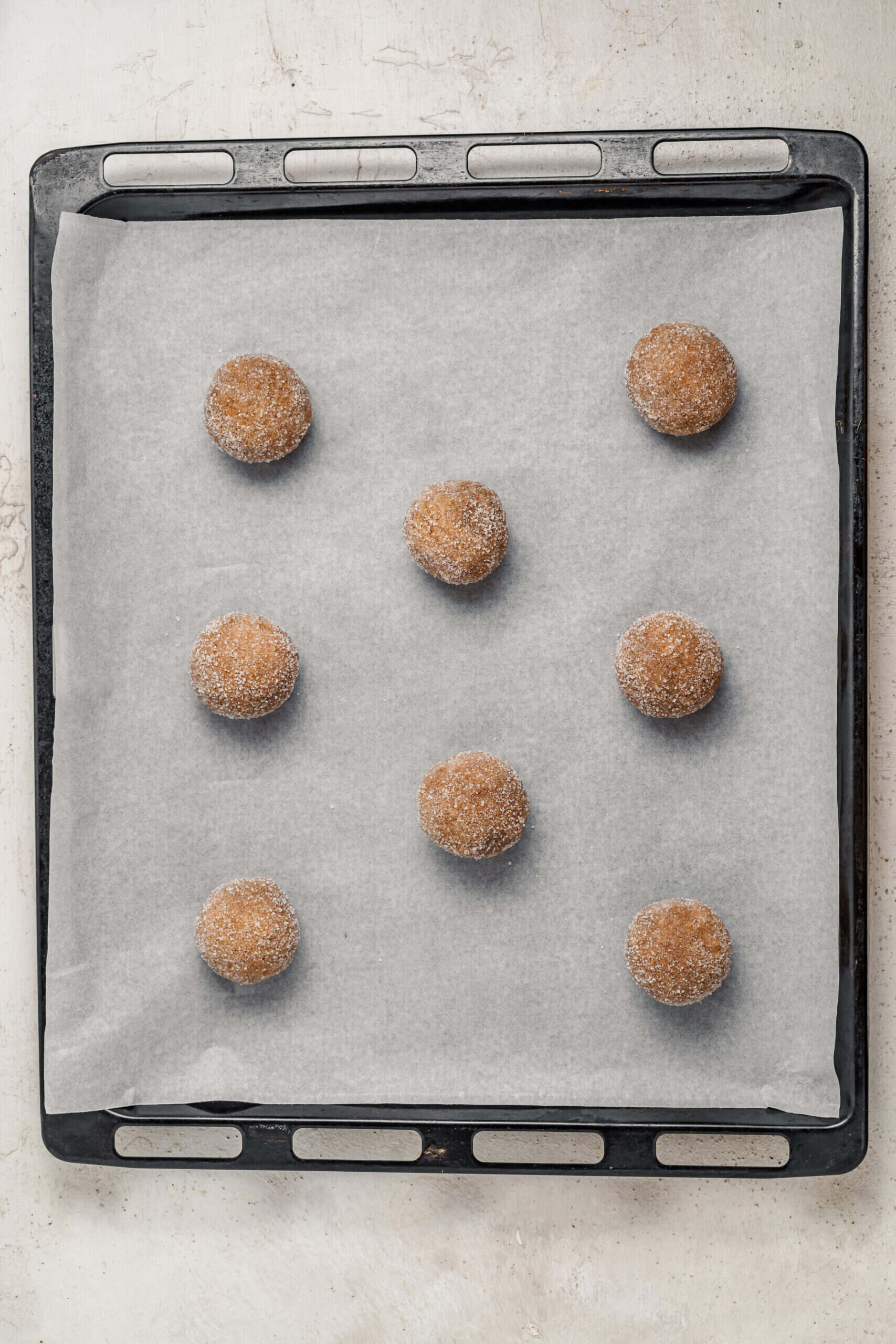 Sugar rolled dough balls spaced on a lined baking sheet - Catherine Zhang Sugar rolled dough balls spaced on a lined baking sheet