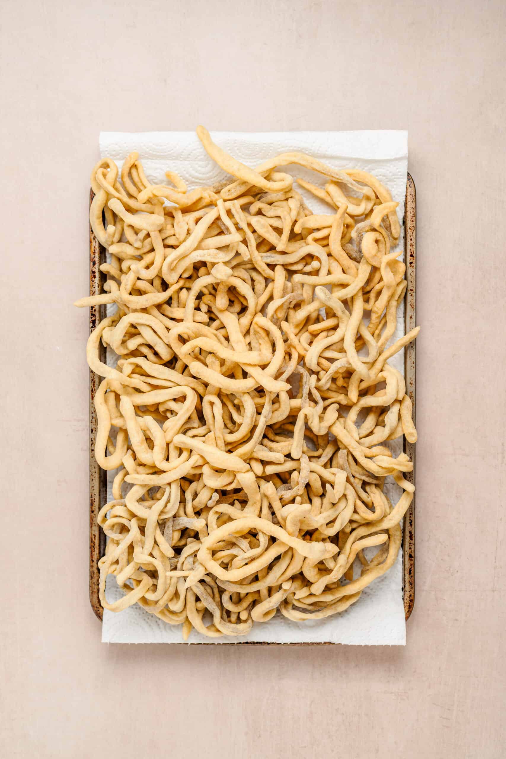 Fried Sachima Noodles - Catherine Zhang Pale gold fried egg noodles for sachima draining on paper
