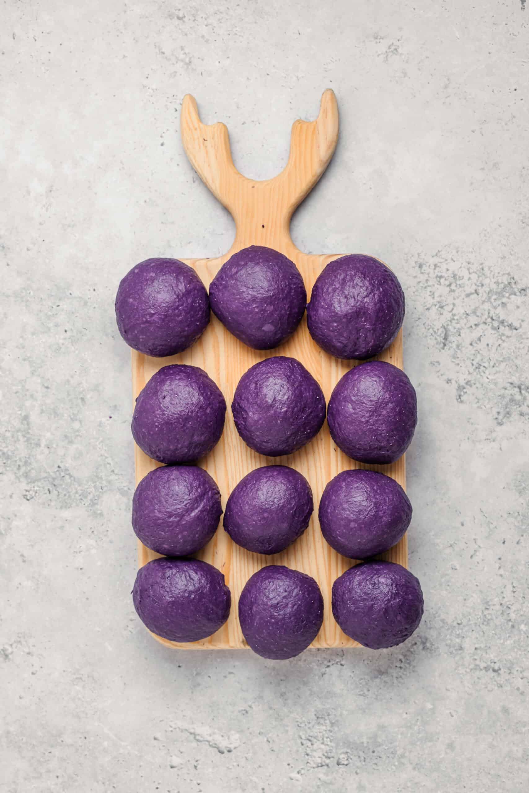 Divided Ube Pandesal Dough - Catherine Zhang Purple ube pandesal dough divided into twelve equal balls on a board