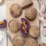 Ube cheese pandesal rolls on a board with one split open beside a mug of Filipino coffee