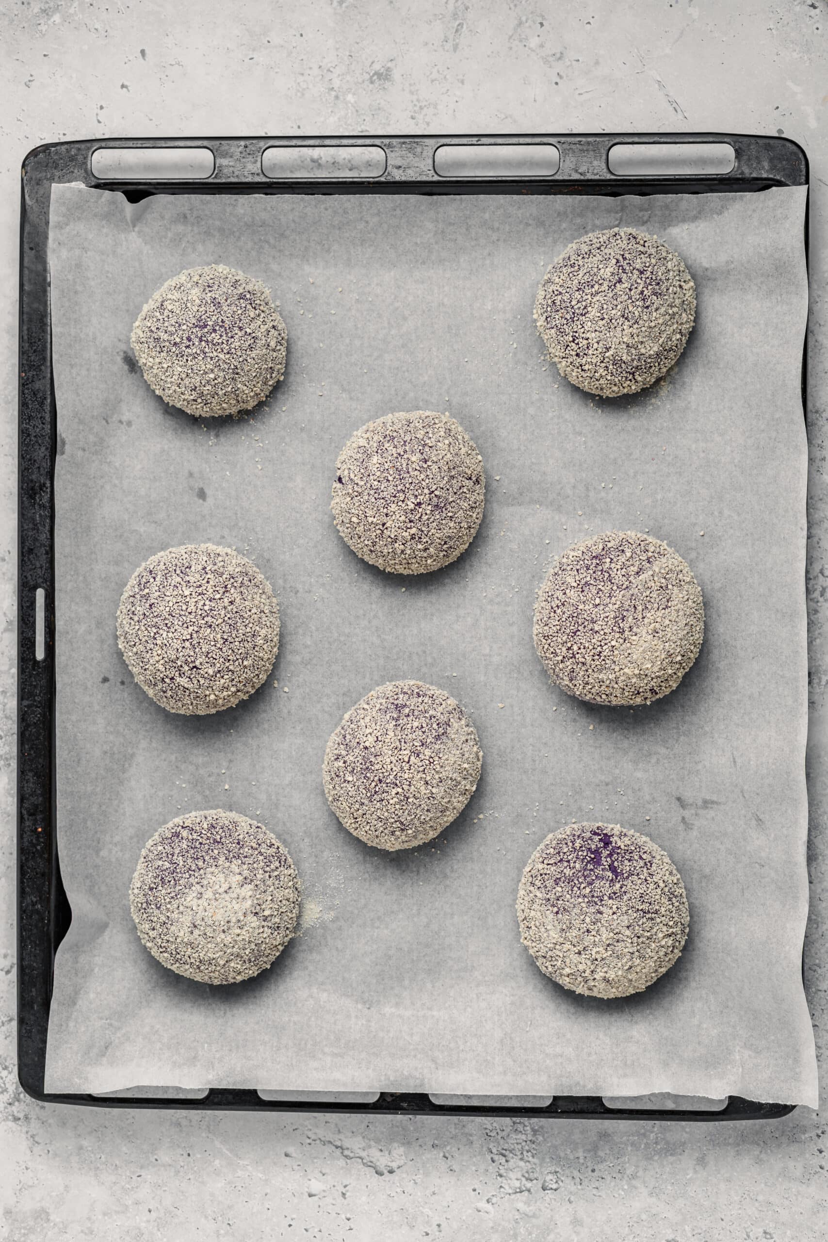 Shaped Ube Pandesal Rolls - Catherine Zhang Breadcrumb coated ube pandesal rolls proofing on a parchment lined tray