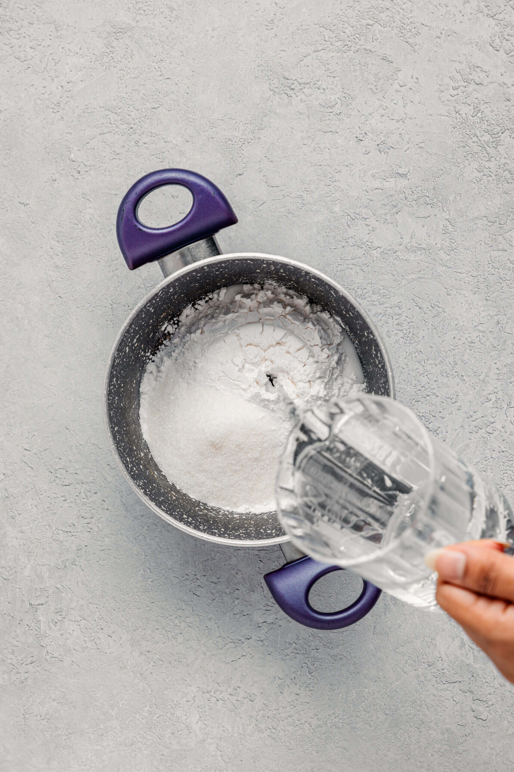 Pouring water into bracken starch and sugar in a saucepan for warabimochi - Catherine Zhang Pouring water into bracken starch and sugar in a saucepan for warabimochi