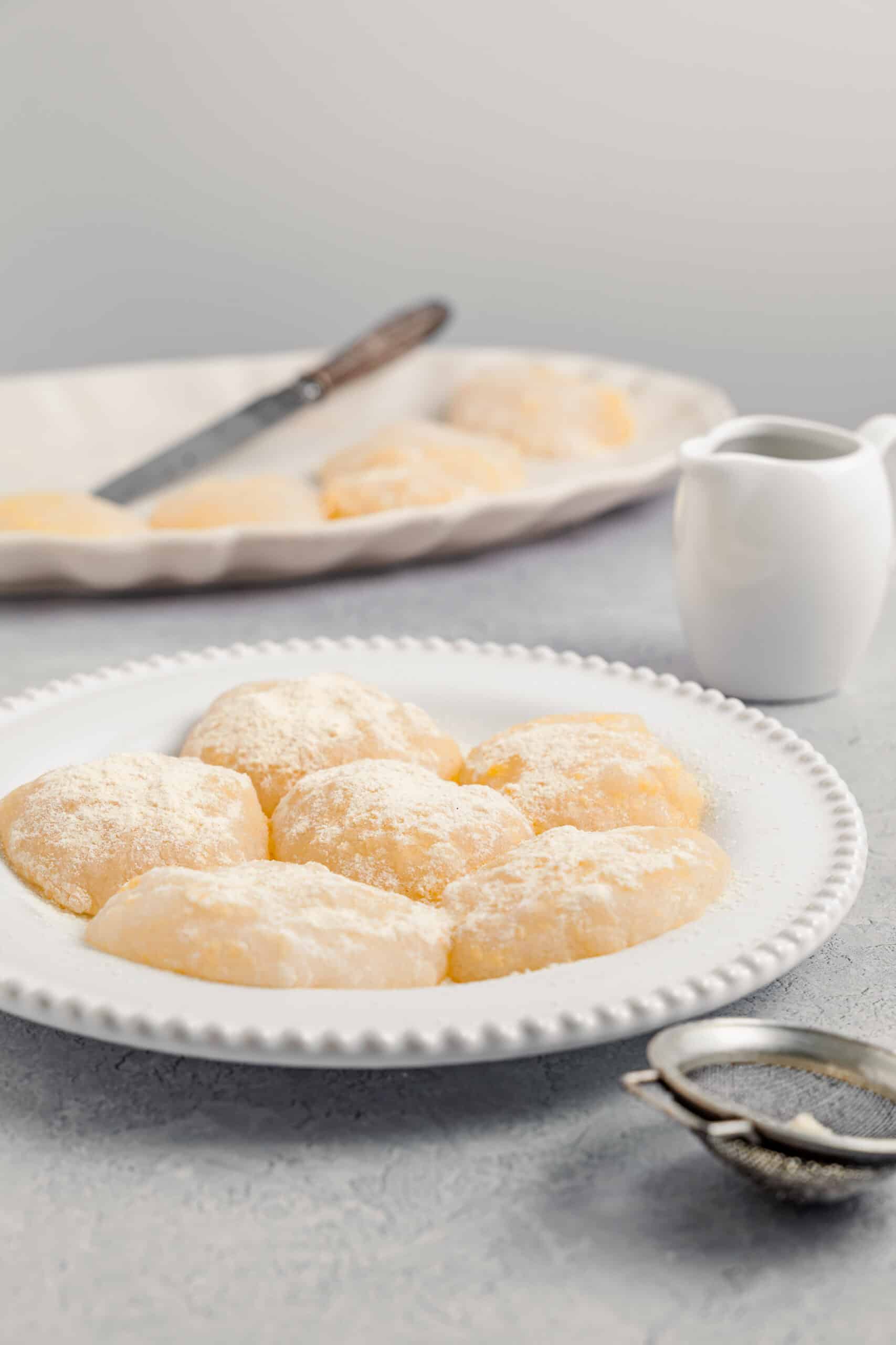 Warabimochi pieces cut and dusted generously with kinako on a white plate - Catherine Zhang Warabimochi pieces cut and dusted generously with kinako on a white plate
