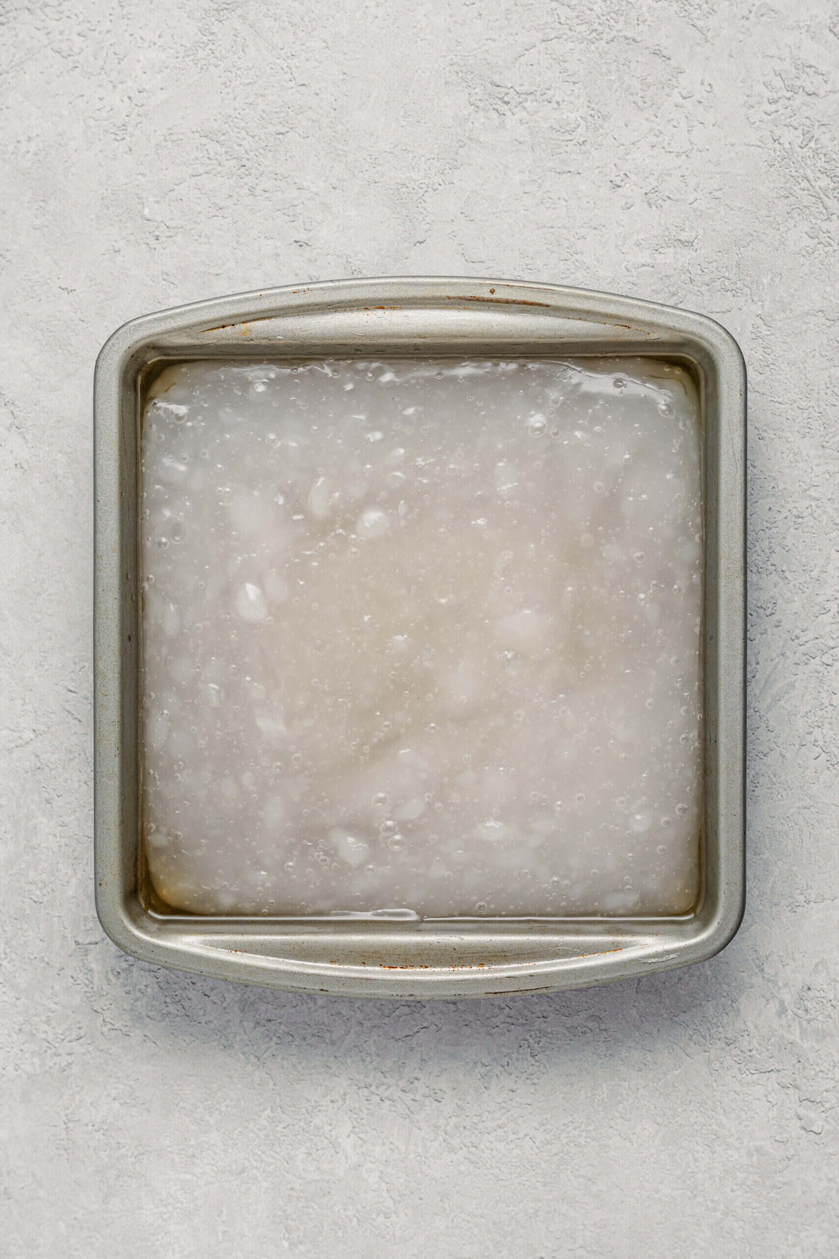 Cooked warabimochi spread into a lined square tin to cool and set - Catherine Zhang Cooked warabimochi spread into a lined square tin to cool and set