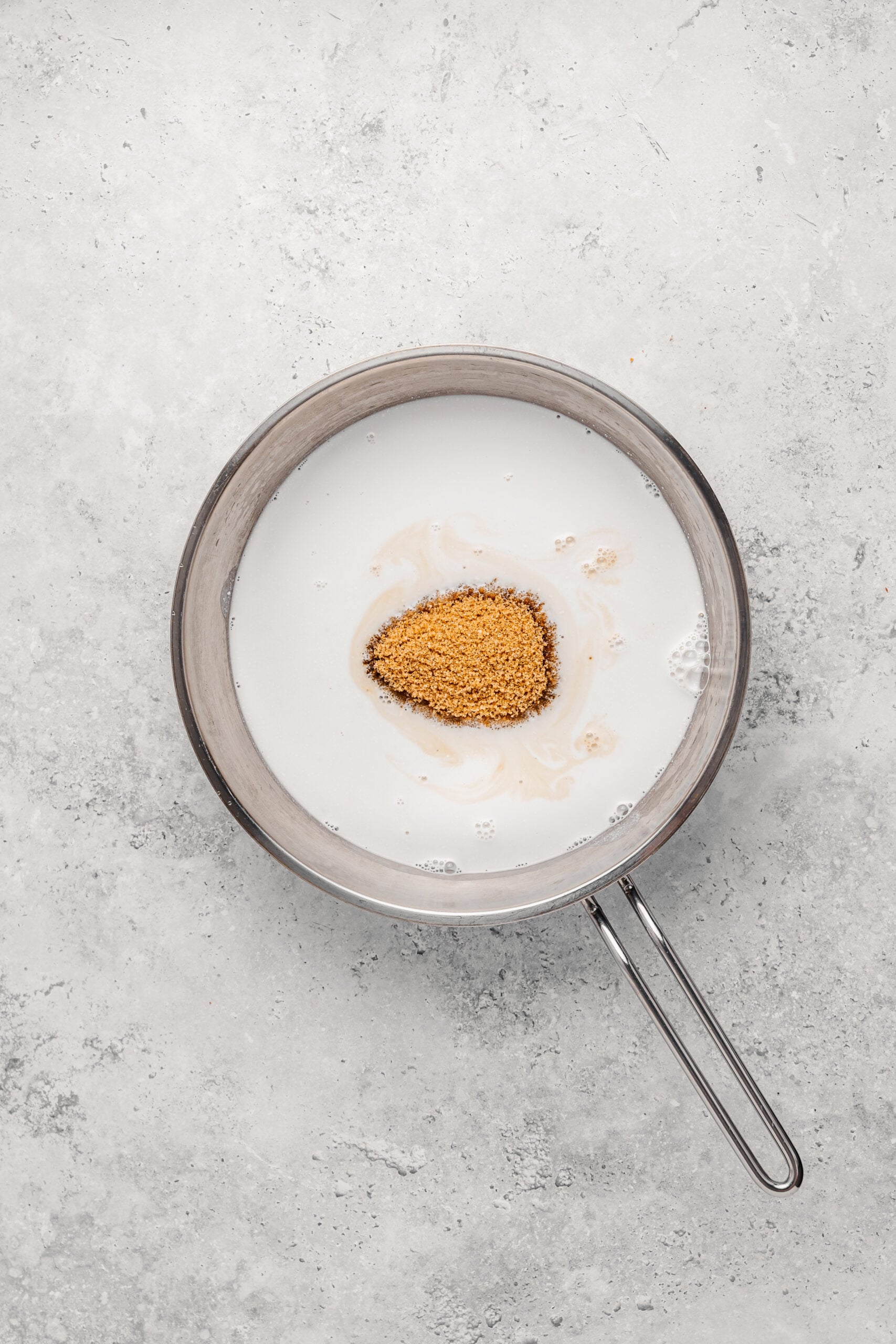 Coconut milk and dark brown sugar in a wide pan for the biko caramel base - Catherine Zhang Coconut milk and dark brown sugar in a wide pan for the biko caramel base