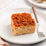 Square of Filipino biko sticky rice cake on a white plate topped with crisp golden latik