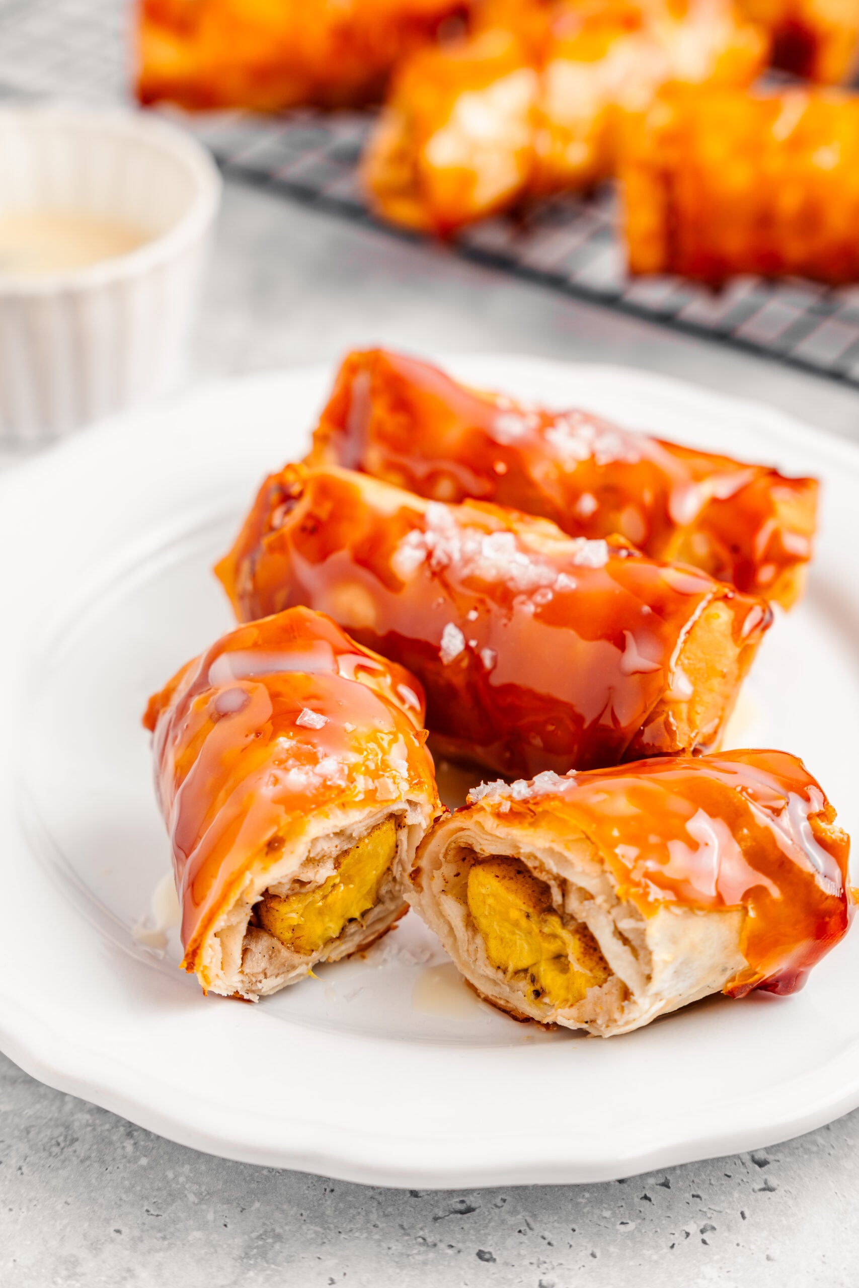 Cut crispy turon showing soft yellow banana inside the blistered caramel shell - Catherine Zhang Cut crispy turon showing soft yellow banana inside the blistered caramel shell