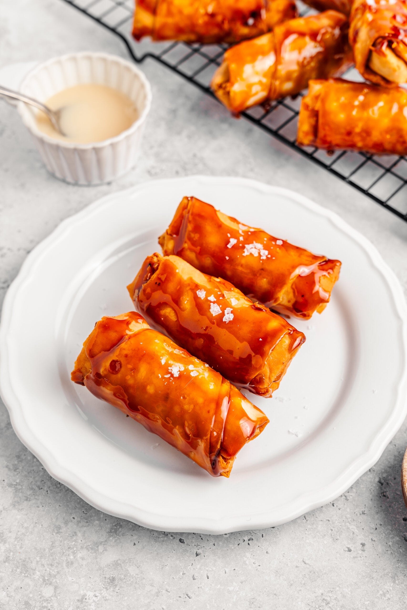 Plate of crispy turon drizzled with condensed milk and finished with flaky salt - Catherine Zhang Plate of crispy turon drizzled with condensed milk and finished with flaky salt