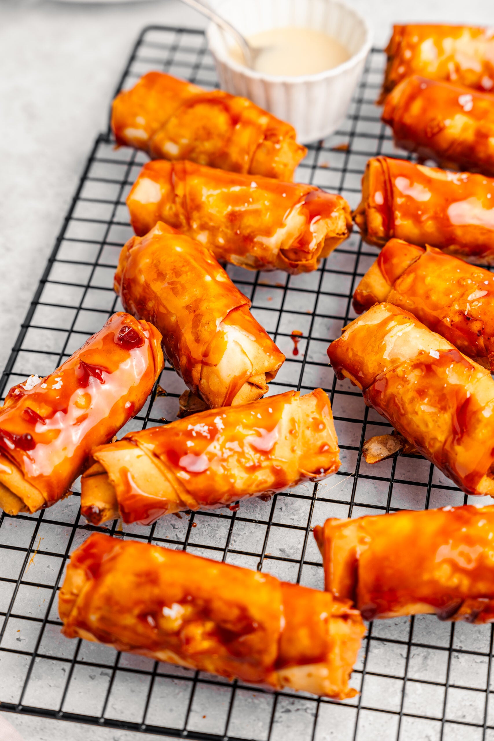Angled view of caramel lacquered turon cooling on a wire rack - Catherine Zhang Angled view of caramel lacquered turon cooling on a wire rack