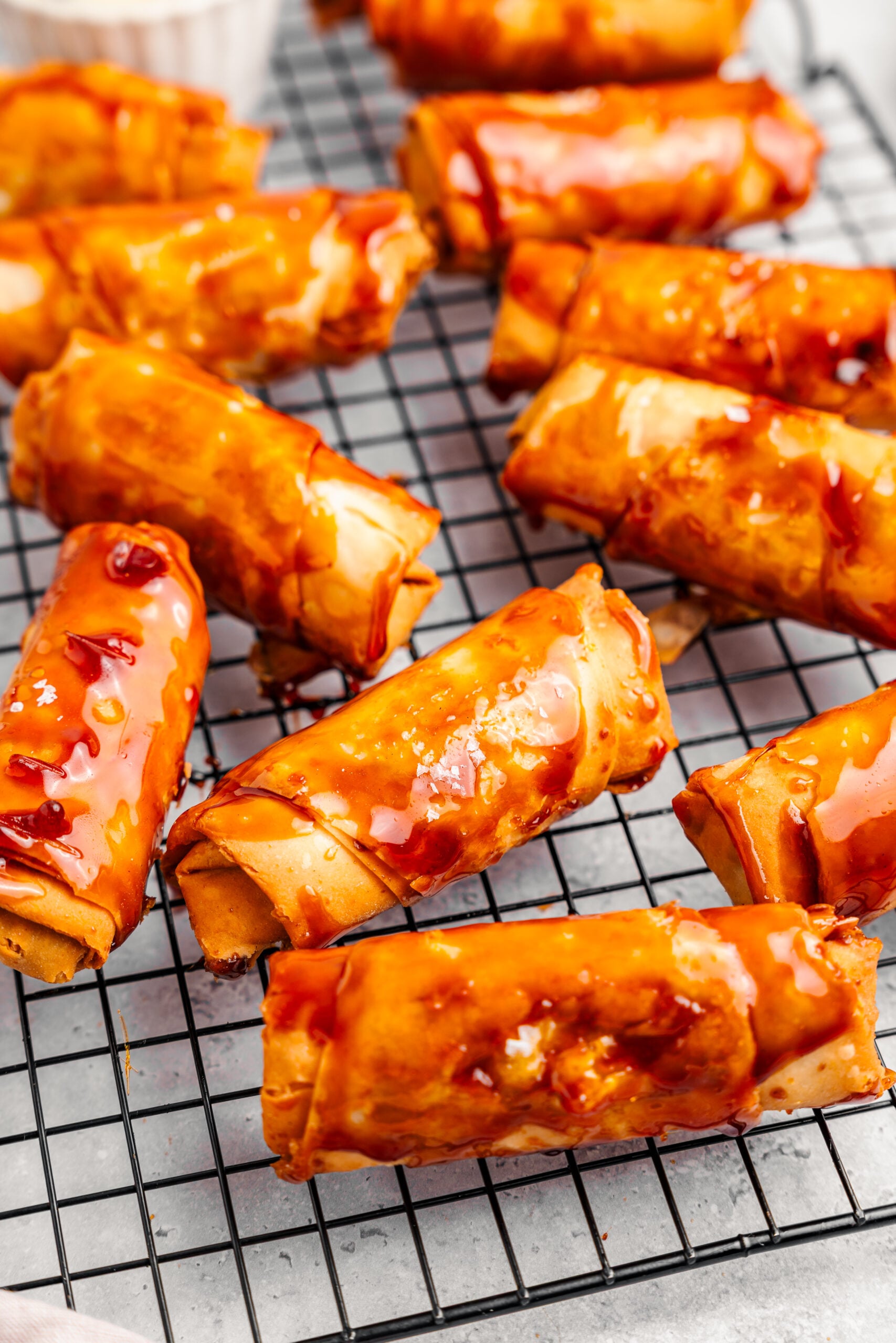 Caramel coated turon rolls resting on a wire rack with flaky salt - Catherine Zhang Caramel coated turon rolls resting on a wire rack with flaky salt
