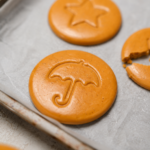 Dalgona candy discs with umbrella and star stamps on a baking tray