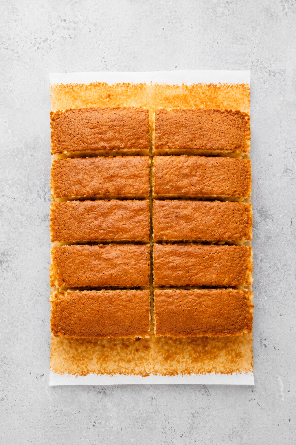 Japanese castella cake sliced into ten thick fingers on baking paper - Catherine Zhang Japanese castella cake sliced into ten thick fingers on baking paper