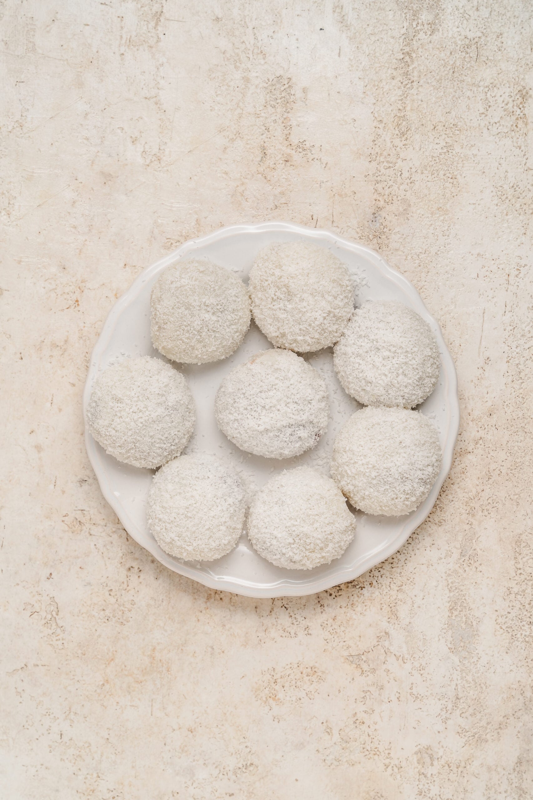 Finished red bean mochi rolled in desiccated coconut on a plate - Catherine Zhang Finished red bean mochi rolled in desiccated coconut on a plate