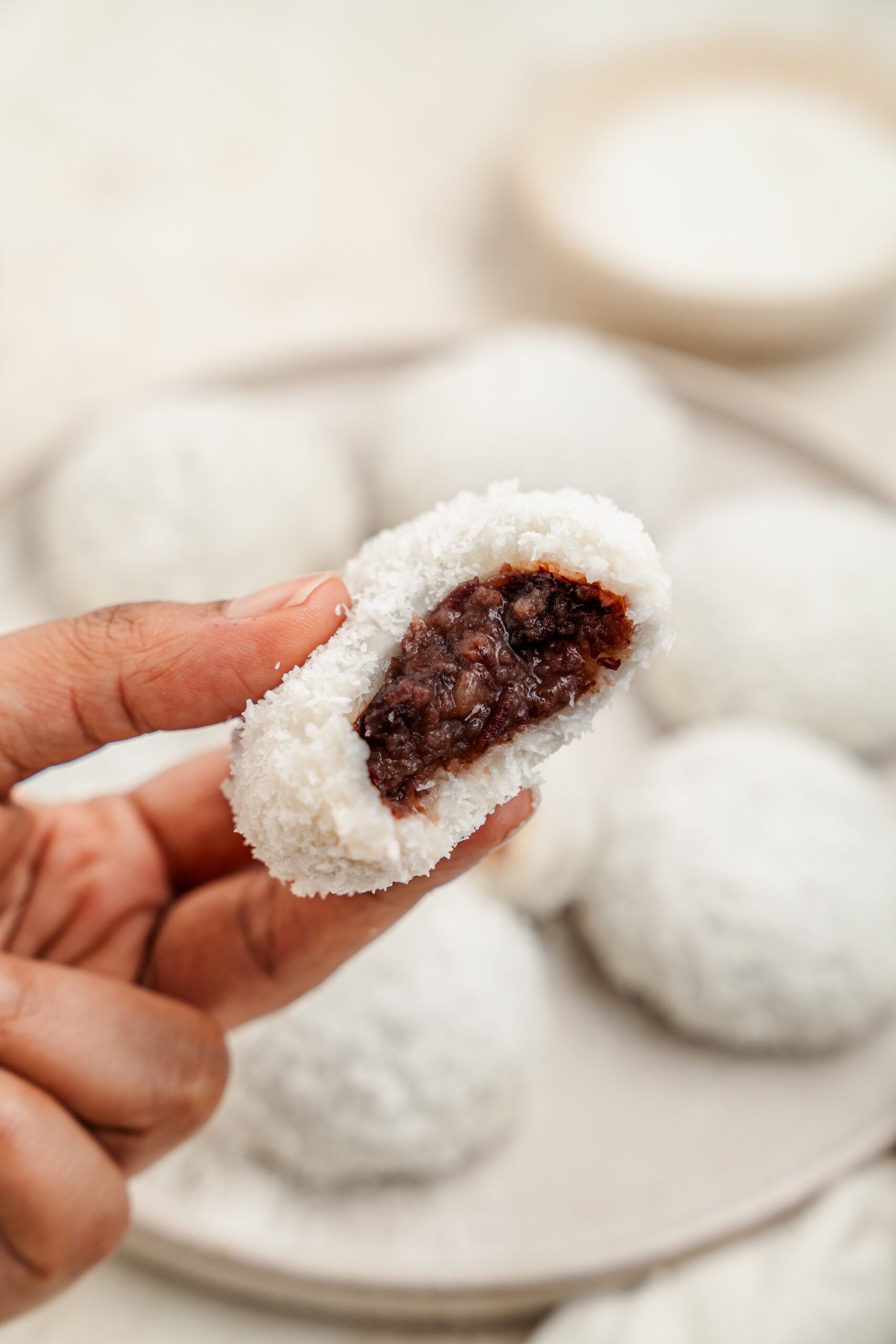 Hand holding a red bean mochi cut open to show the filling - Catherine Zhang Hand holding a red bean mochi cut open to show the filling