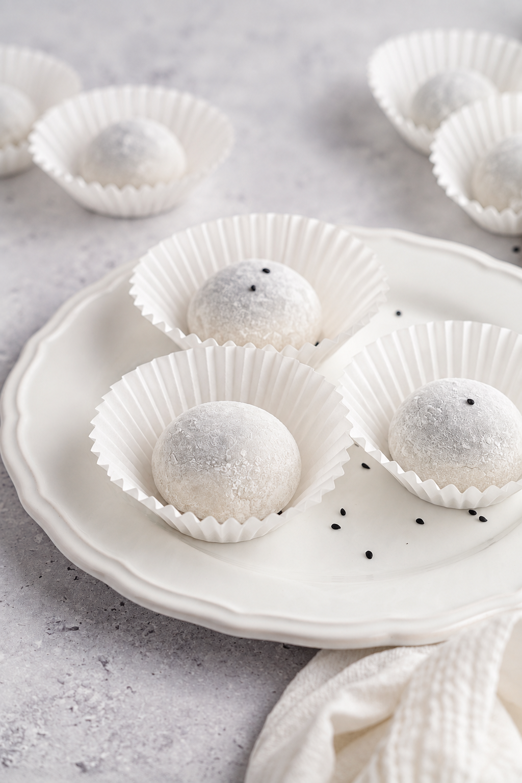 Black sesame mochi recipe - Catherine Zhang Soft black sesame mochi rounds on a white plate with a linen napkin