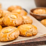 Chinese almond cookies with a whole almond in the centre of each, piled on baking paper