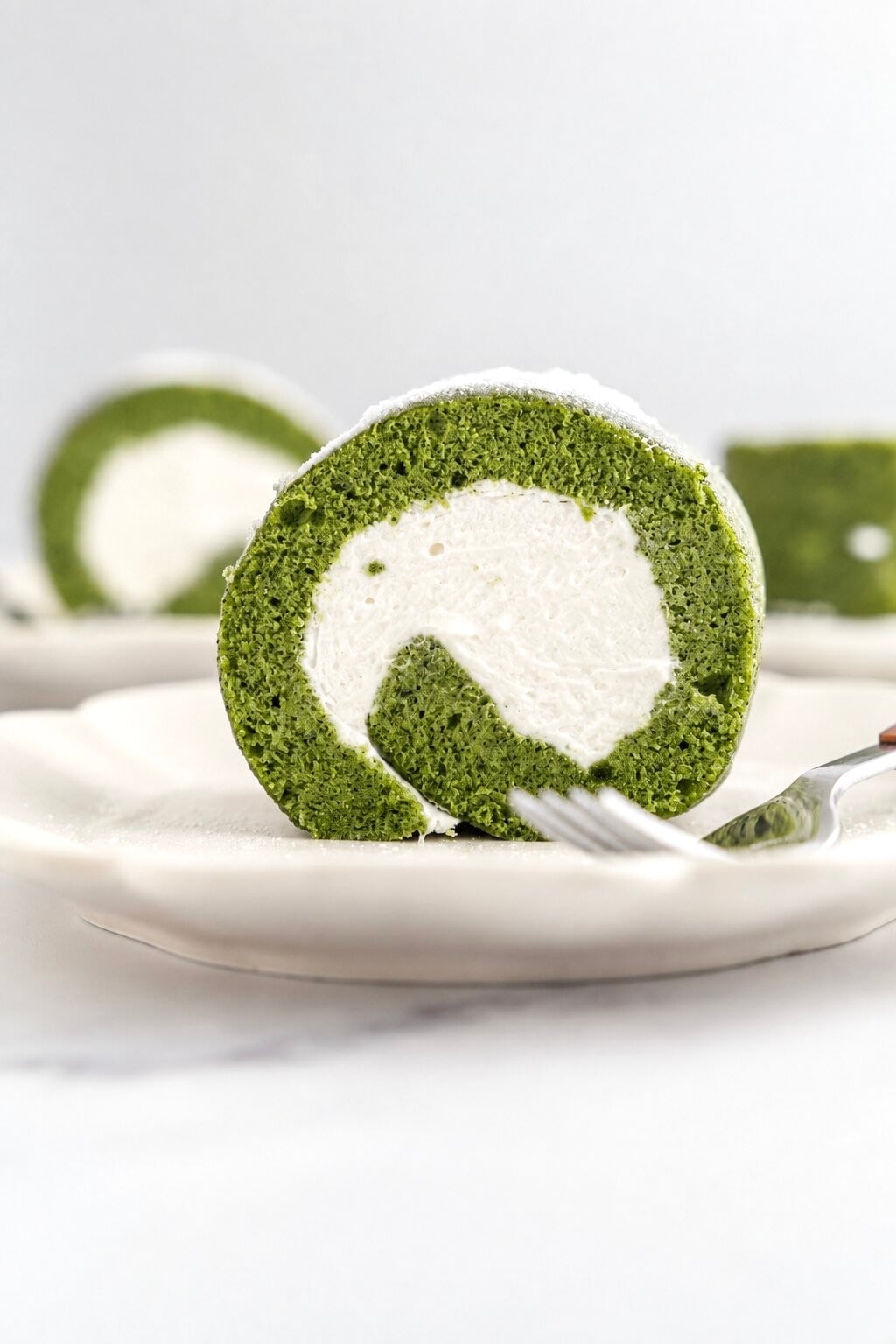 Matcha roll cake recipe - Catherine Zhang Matcha roll cake slices on white plates dusted with icing sugar