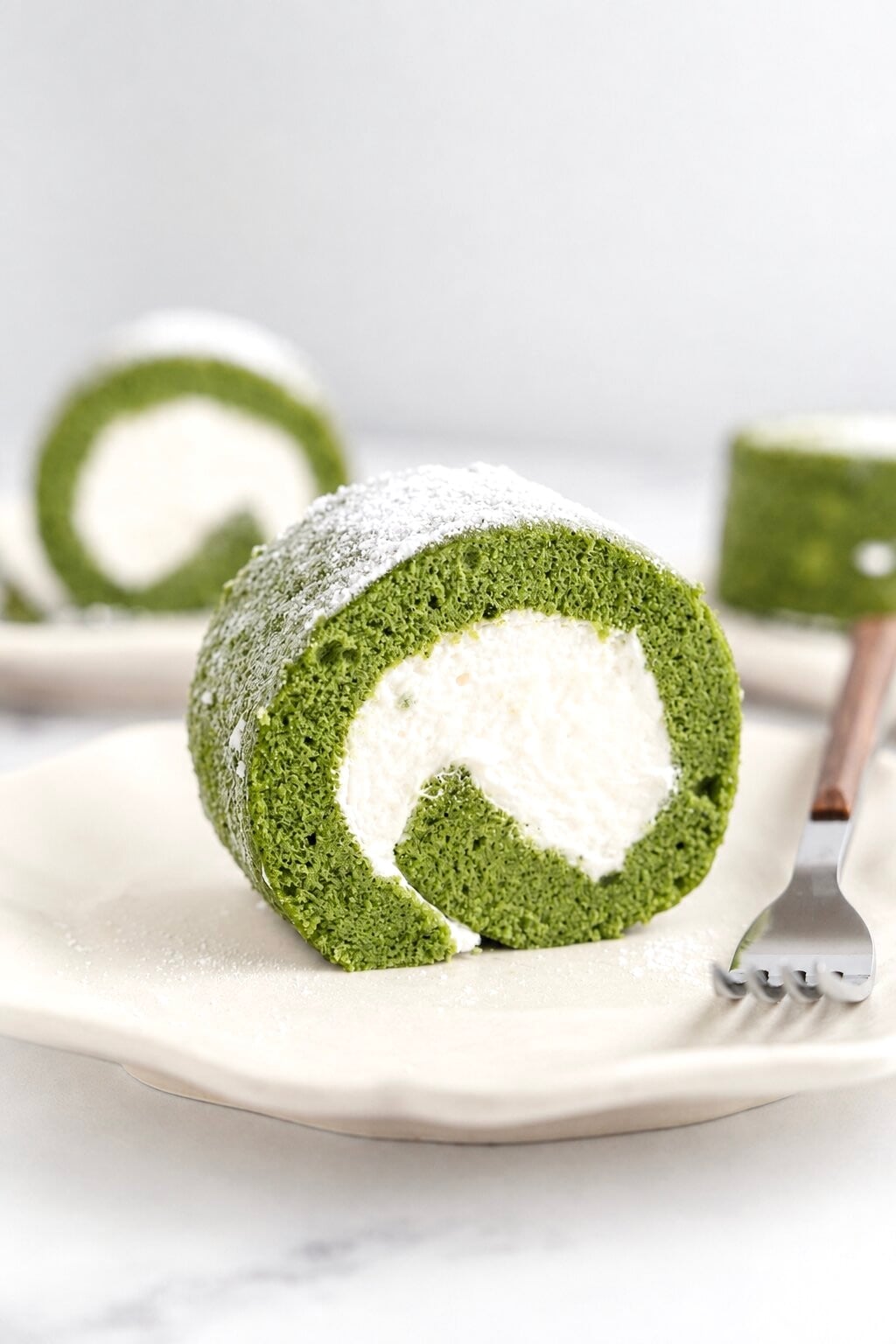 Matcha roll cake - Catherine Zhang Matcha roll cake slice showing a tight cream spiral inside a green sponge