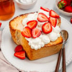 Shibuya honey toast topped with whipped cream and strawberries on a white plate