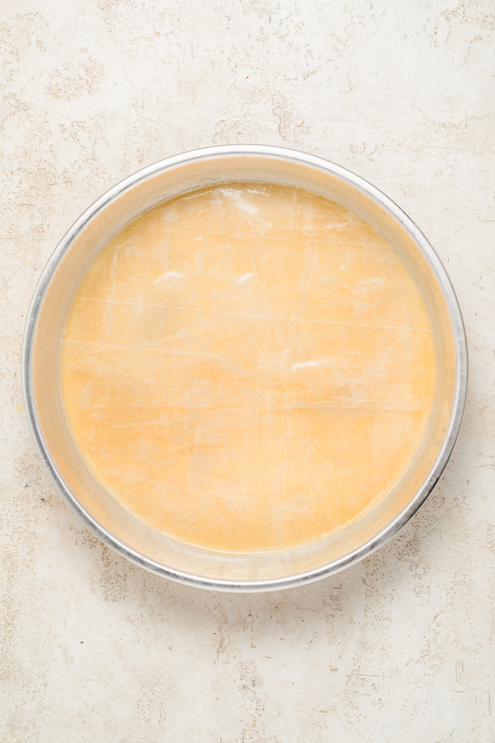 Buttered phyllo base for baklava - Catherine Zhang Ten buttered phyllo sheets stacked in the base of a baking tin