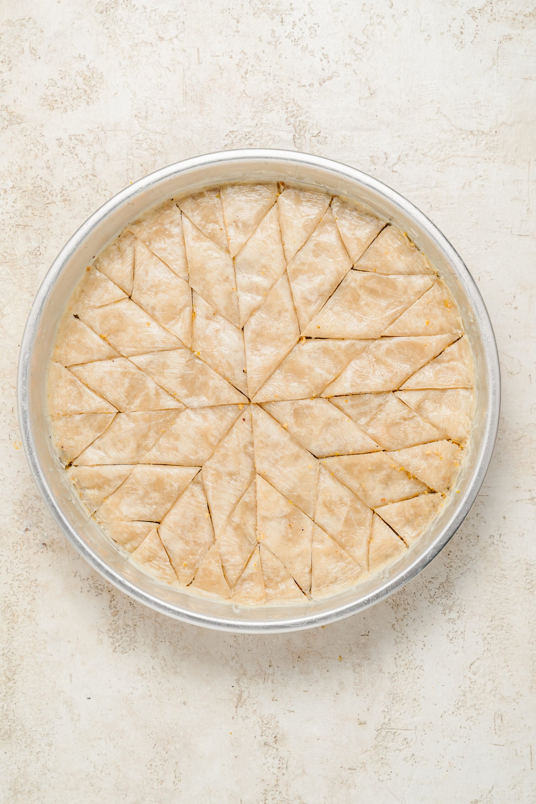 Baklava cut into diamonds before baking - Catherine Zhang Raw baklava cut all the way to the base of the tin in a diamond pattern before baking