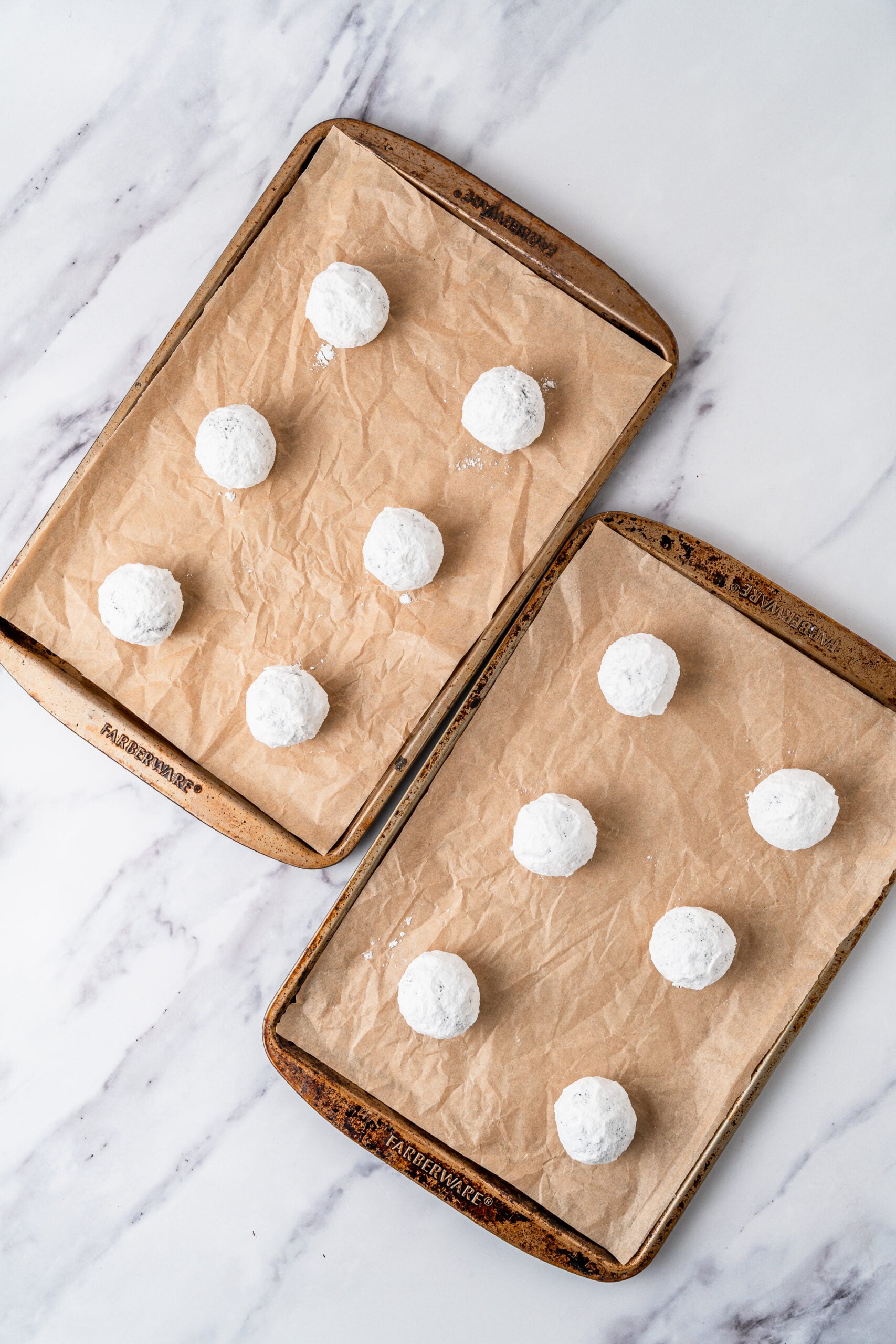 chocolate-crinkle-cookies-dough-balls-on-tray - Catherine Zhang White coated chocolate crinkle cookie dough balls spaced on two lined baking trays
