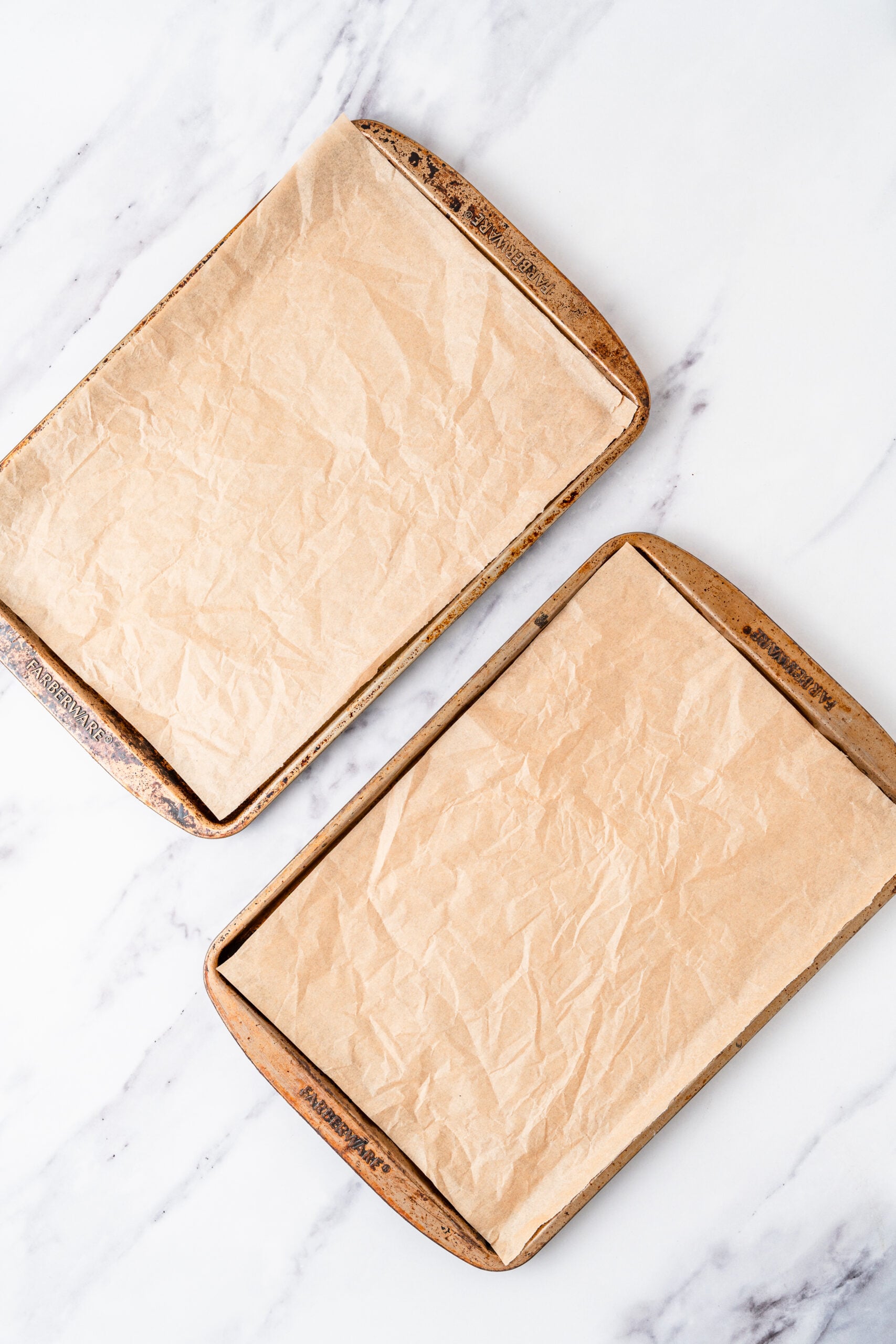 chocolate-crinkle-cookies-lined-baking-trays - Catherine Zhang Two baking trays lined with parchment ready for chocolate crinkle cookies