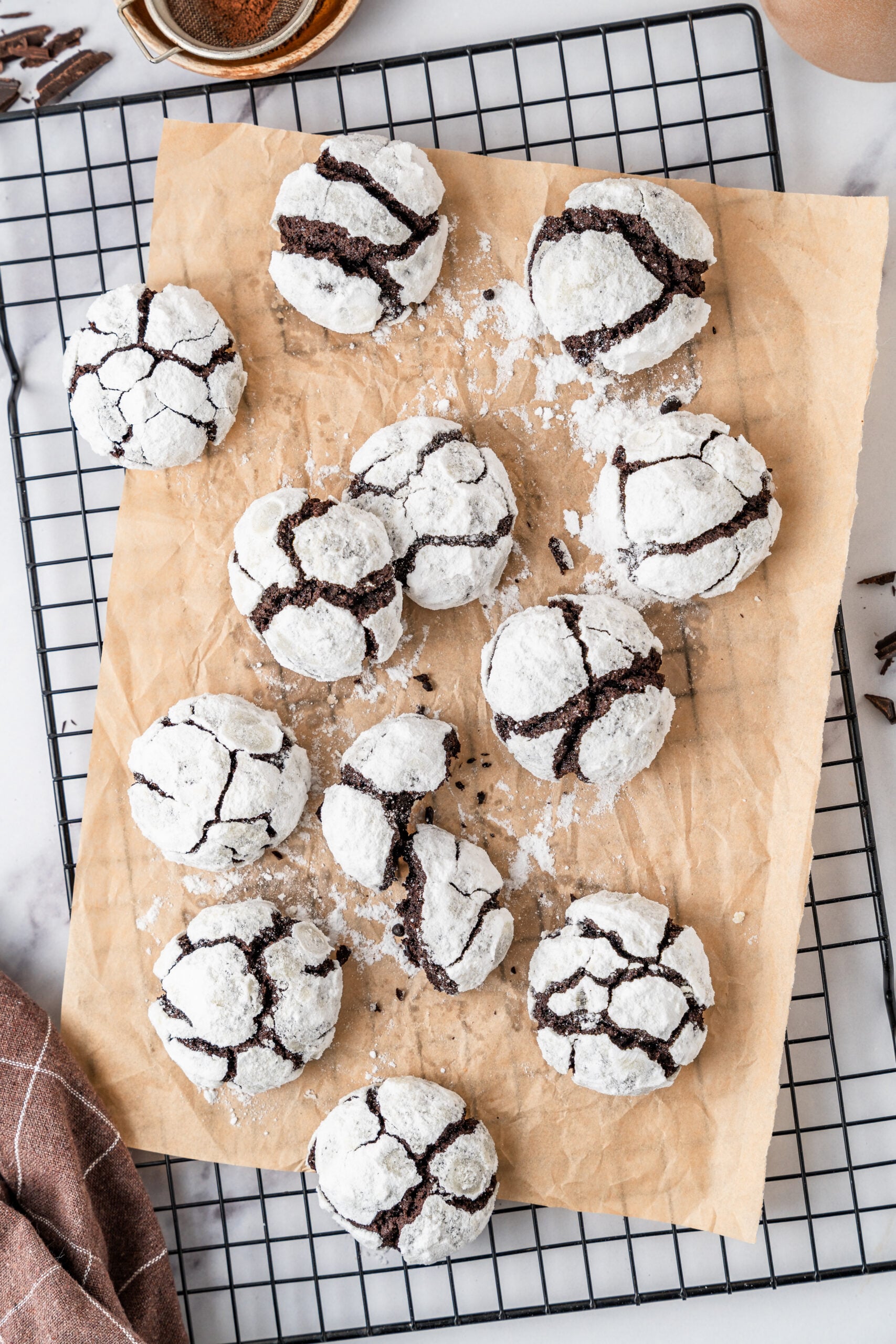 chocolate-crinkle-cookies-overhead - Catherine Zhang Overhead view of chocolate crinkle cookies cooling on parchment