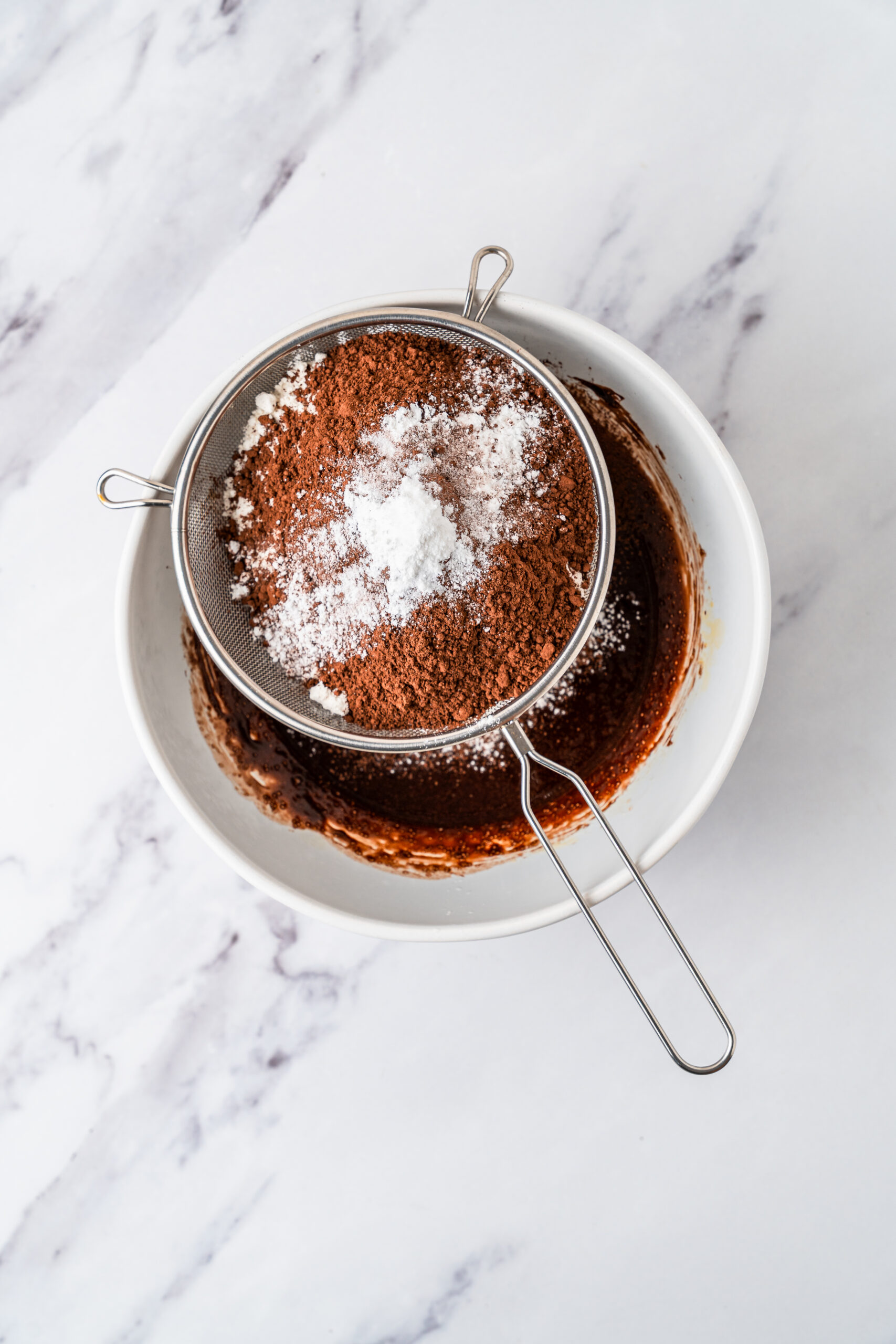 chocolate-crinkle-cookies-sifting-cocoa - Catherine Zhang Flour, Dutch process cocoa and baking powder sifted over the chocolate crinkle cookie batter