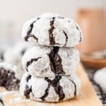 A stack of three chocolate crinkle cookies on parchment over a wire rack